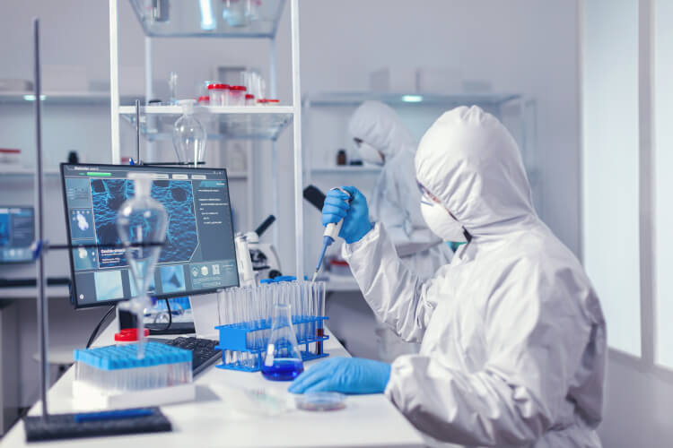 Laborant met veiligheidskleding zoals handschoenen en mondkapje werkt in een laboratorium